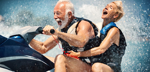 Elderly couple having a blast riding a jet ski.
