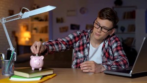 A young boy putting money into a piggy bank.