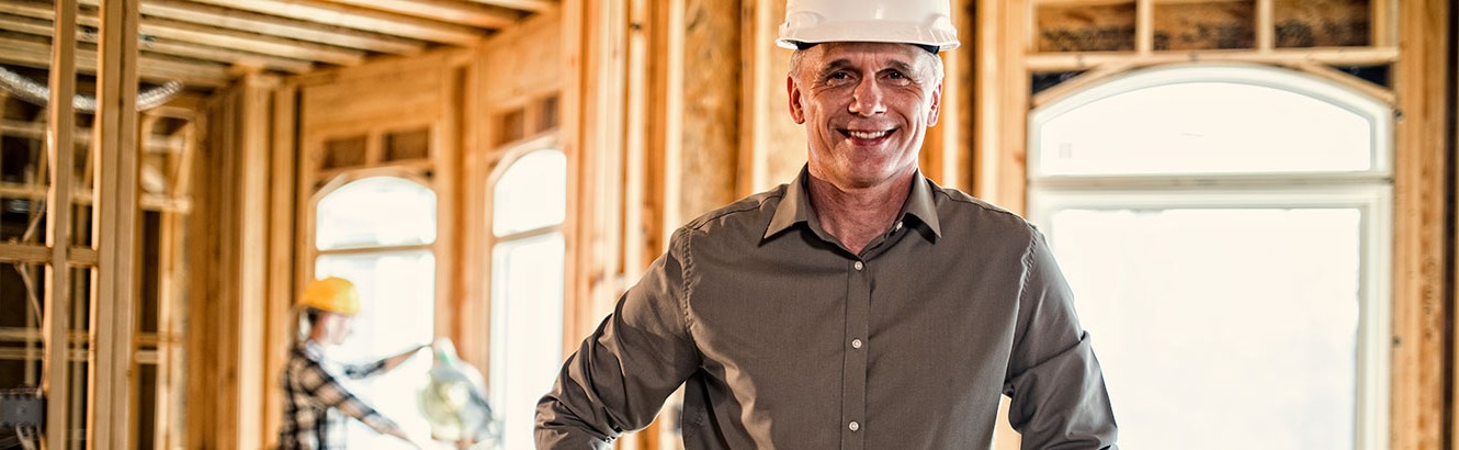 Man in a house under construction wearing a hard hat. 