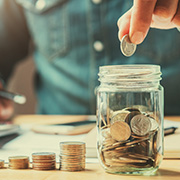 A man putting stacks of coins into a jar.