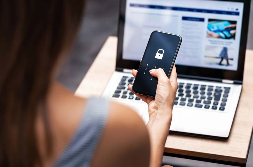 A woman unlocking her phone while using a laptop