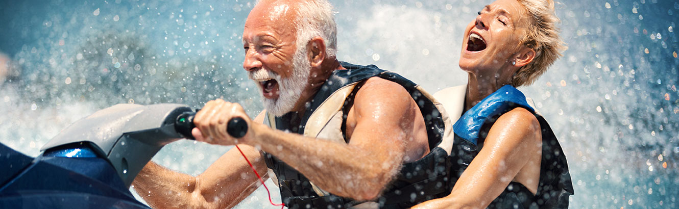 Elderly couple having a blast riding a jet ski.