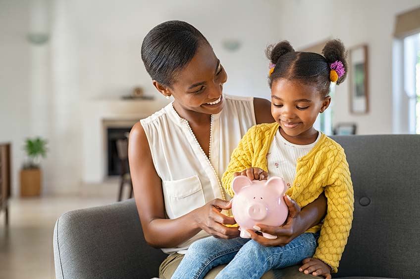 Mother and daughter saving money in a piggy bank