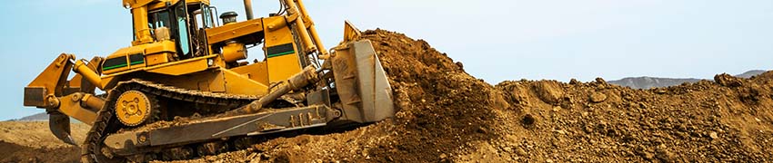 A bulldozer plowing dirt on a hill as part of a construction project