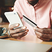 A man holding his phone in one hand and his credit card in the other to review his finances.