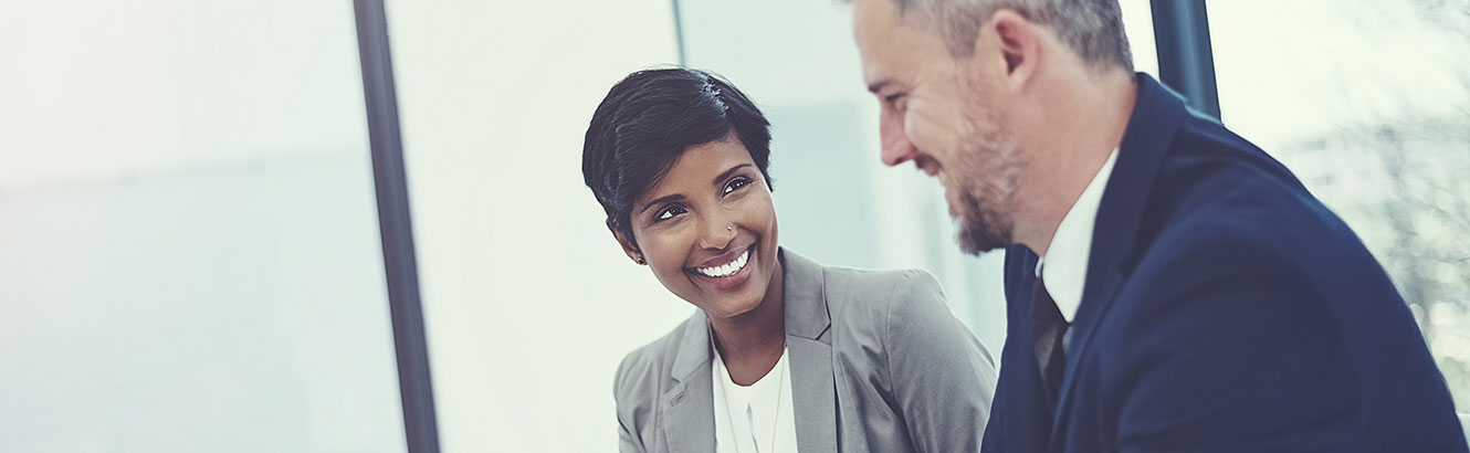 Woman and a man discussing papers at a desk. 