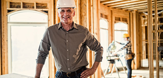 Man in a house under construction wearing a hard hat. 