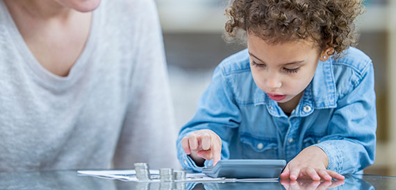 Small child using a calculator and counting change. 