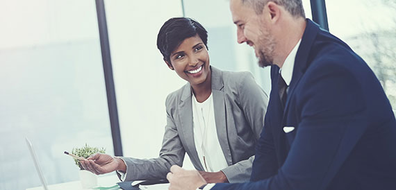 Woman and a man discussing papers at a desk. 