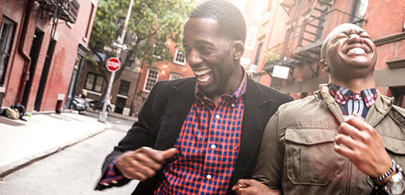 Two men walking down a street laughing.